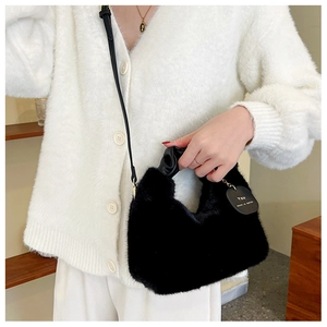Detail of black plush faux fur handbag with twisted handle and heart leather charm