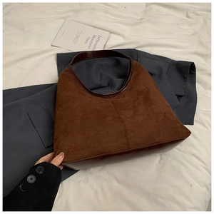 Detail van donkerbruine suède hobo tas met lederen bies en een vintage uitstraling