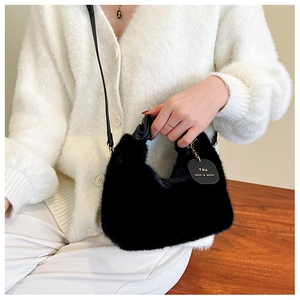 Détail du sac en fausse fourrure noire avec anses en cuir et étiquette décorative