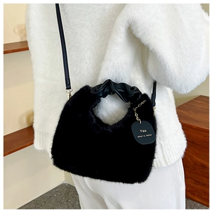 Détail du sac bandoulière en fausse fourrure noire avec poignée en cuir plissé
