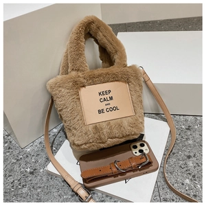 Detail of plush brown faux fur tote bag with leather text patch and crossbody strap