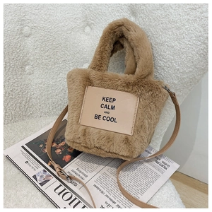 Detail of plush brown tote bag with leather patch slogan on soft faux fur texture