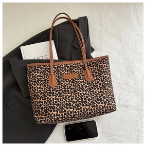 Flat lay of a leopard print tote bag with brown straps on a stylish office setting