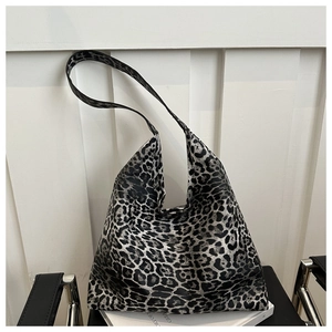 Detail of a large leopard print tote bag placed on a white book in a minimalist setting