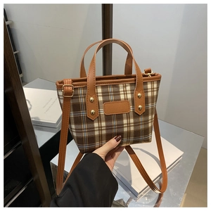 Detail of vintage brown plaid bucket bag with adjustable strap and contrast leather trim