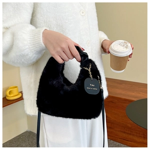 Detail of plush black faux fur handbag with leather handle and engraved gold tag