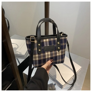 Close-up of blue and brown plaid tweed crossbody bag with black leather handle and trim