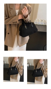 Close-up of a black faux suede Boston bag with double handles in a vintage retro style