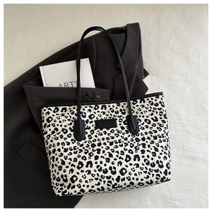 Detail view of large leopard print tote bag on textured fabric with urban styling