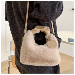 Detail of soft beige faux fur handbag with ruched leather handle and branded tag