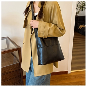 Minimalist black PU leather bucket bag with cross-stitch details shown on model