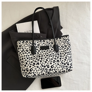 Flat lay of a large leopard print tote bag with black straps and fashion accessories
