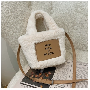 Detail of plush white tote bag with brown leather patch and adjustable shoulder strap