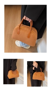 Detail of brown suede Boston bag with smooth orange leather straps and top metal zipper