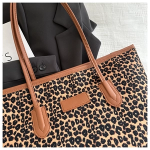 Close-up of leopard print canvas tote bag with premium brown leather strap and stitching