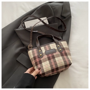 Detail of plaid tote bag featuring brown and pink checkered fabric with golden rivets