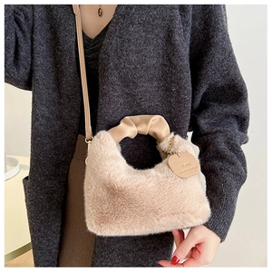 Détail du sac à main en peluche beige avec poignée en cuir froncée et étiquette