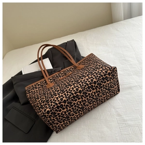Detail of high-capacity leopard print tote bag with brown straps on a white sheet