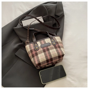 Detail view of plaid tote bag featuring leather handles and adjustable shoulder strap