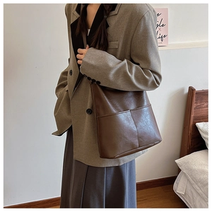 Detail of vintage brown leather tote bag showing textured surface and front pockets