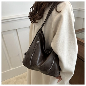 Detail of vintage brown tote bag showing side capacity and silver dual zippers on model