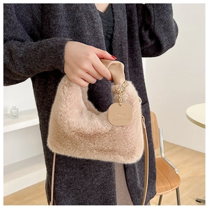 Detail of khaki plush handbag with leather handle and decorative gold chain tag