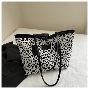 Detail of large tote bag with leopard print on textured white fabric next to a blazer