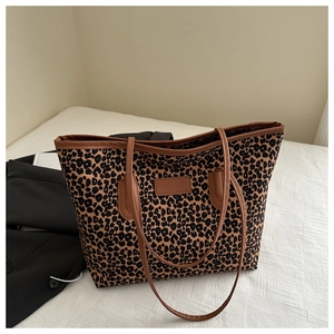 Macro shot of the leopard print pattern and brown leather trim on a retro tote bag