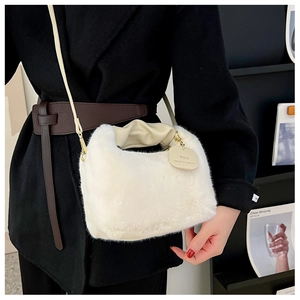 Close-up of white faux fur handbag featuring a gold pendant with engraved text