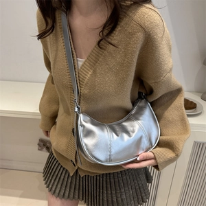 Minimalist silver crescent hobo bag made of metallic PU leather worn by a female model