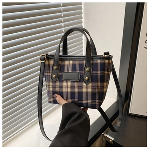 Detail of vintage plaid tote bag with black leather handles and metallic studs
