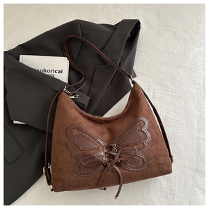 Close-up of brown suede shoulder bag featuring a unique butterfly leather patch detail