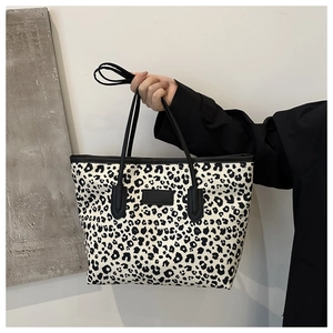 Detailed view of large leopard print tote bag with black straps held by model
