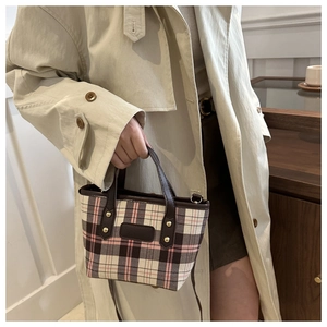 Retro plaid handbag with brown leather trim held by a model in a beige trench coat