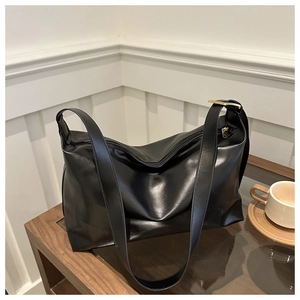 Détail du sac cabas en cuir noir brillant avec fermeture éclair dorée et bandoulière