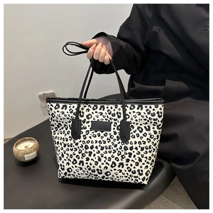 Close-up of leopard print tote bag with black leather straps and detachable shoulder strap