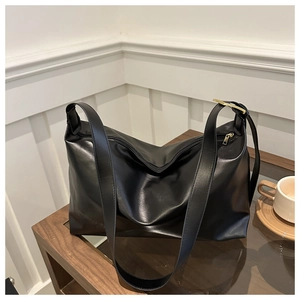 Détail du sac bandoulière noir en cuir PU avec garnitures dorées sur table en bois