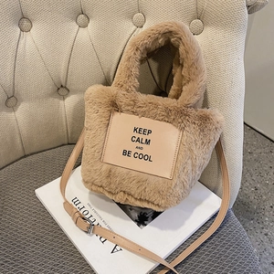 Furry plush tote bag with adjustable strap and 'KEEP CALM' patch on a beige sofa
