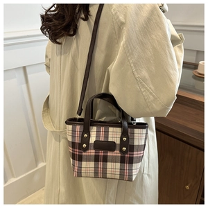 Detail of checkered tote bag showing pink plaid fabric, leather handle and gold rivets