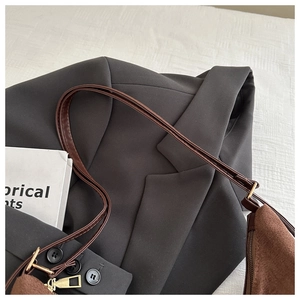 Detailed texture of dark brown suede shoulder bag with polished gold hardware accents