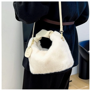 Détail du sac fourrure crème avec poignée en cuir nouée et étiquette en chaîne dorée