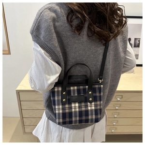 Close-up of classic check pattern shoulder bag with premium leather trim and gold studs