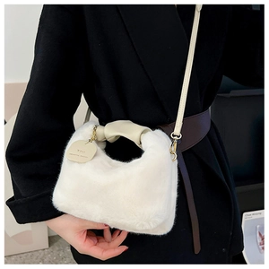Close-up of white plush crossbody bag with gold chain and YOU deserve better tag
