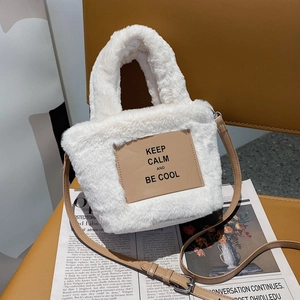 Chic white faux fur crossbody bag with brown leather strap and slogan patch