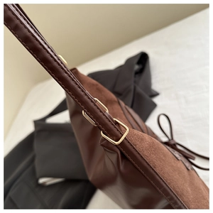 Detail of dark brown leather and suede stitching on tote with gold metal buckle
