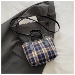 Plaid fabric tote bag with leather handles displayed on a dark grey blazer