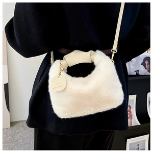 Detail of white faux fur handbag with ruched leather handle and inspirational charm tag