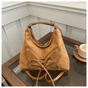 Detail of tan suede tote bag with butterfly leather patch and versatile shoulder straps