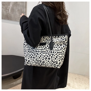 Close-up of leopard print tote bag with black strap and leather tag on shoulder