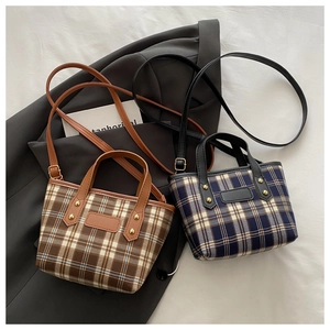 Detail of plaid tote bag featuring leather trim, metallic rivets and adjustable shoulder strap